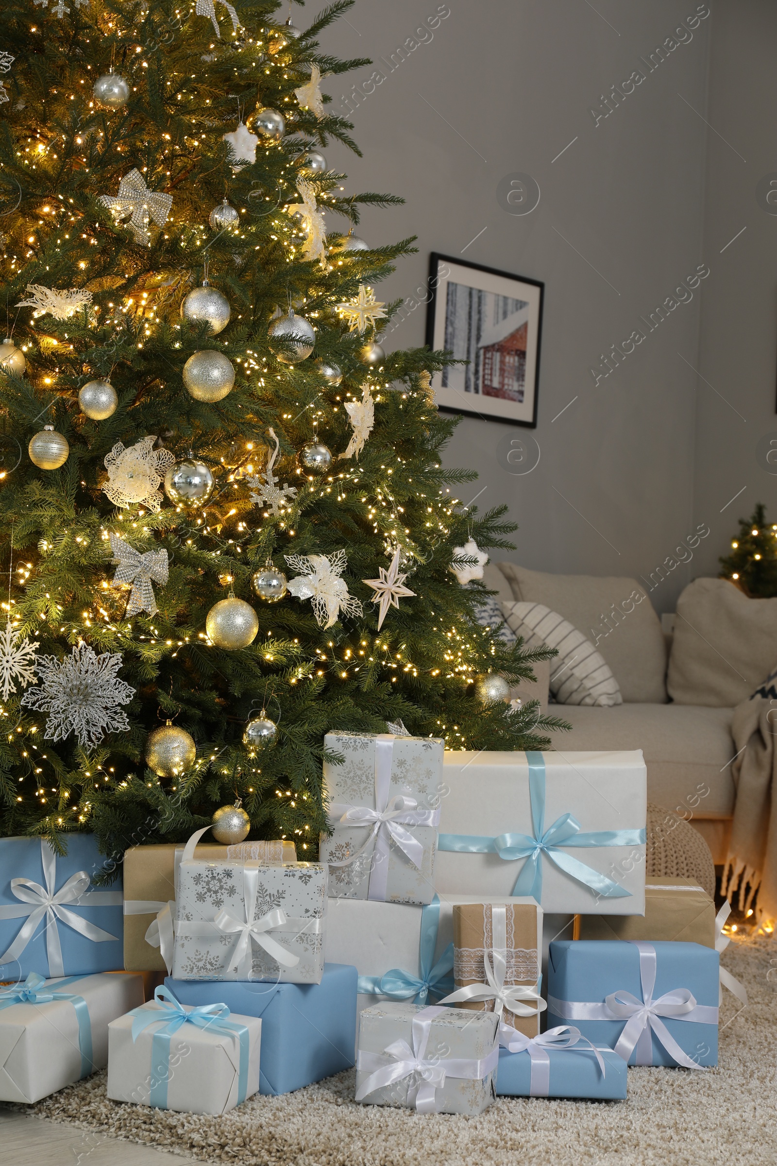 Photo of Many gift boxes under decorated Christmas tree in room