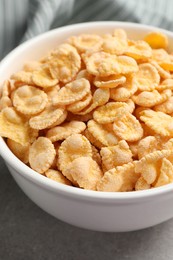 Photo of Bowl of tasty corn flakes on light grey table. closeup
