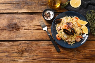 Photo of Delicious pasta with sea food served on wooden table, flat lay. Space for text