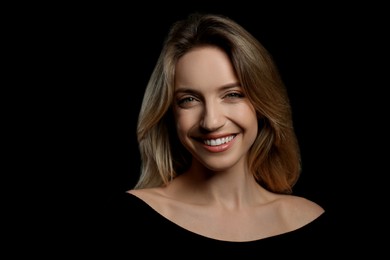 Photo of Portrait of happy young woman with beautiful blonde hair and charming smile on black background