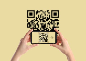 Woman scanning QR code with smartphone on beige background, closeup