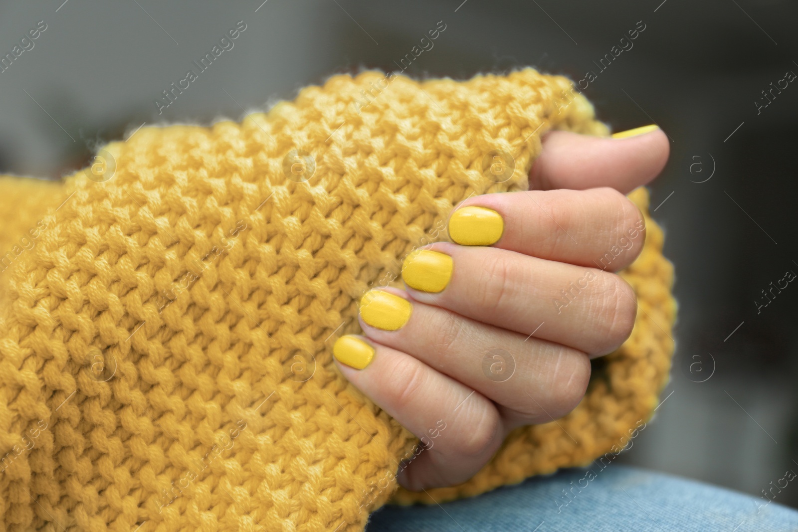 Image of Young woman with stylish yellow manicure and knitted plaid, closeup