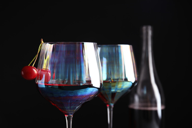 Delicious cherry wine with ripe juicy berries on black background, closeup