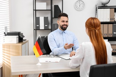 Smiling embassy worker consulting woman about immigration to Germany in office