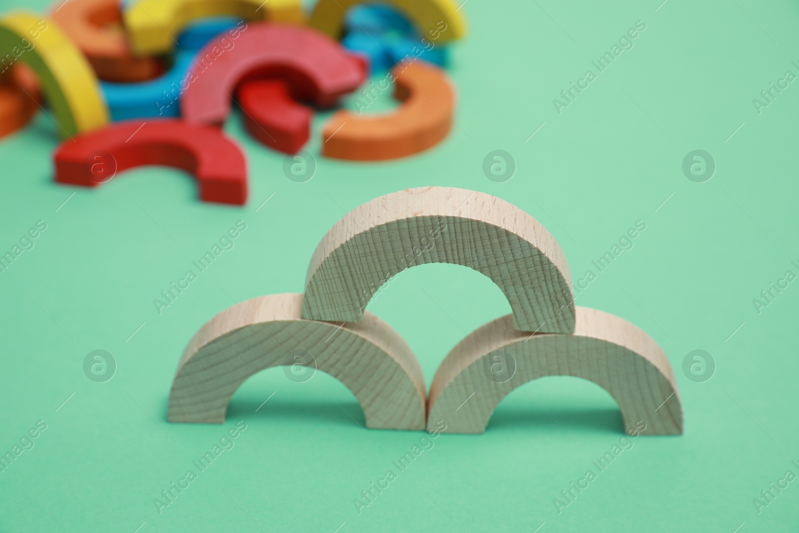 Photo of Wooden pieces of play set on green background, closeup. Educational toy for motor skills development