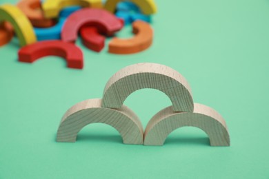 Photo of Wooden pieces of play set on green background, closeup. Educational toy for motor skills development