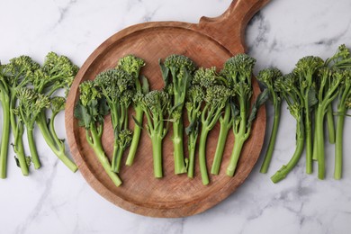 Photo of Fresh raw broccolini on white marble table, flat lay. Healthy food