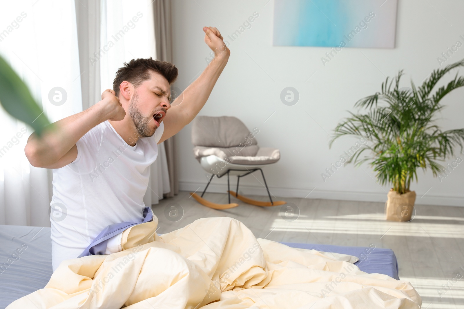 Photo of Handsome man stretching at home in morning, space for text. Bedtime