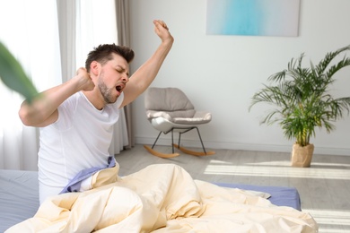 Photo of Handsome man stretching at home in morning, space for text. Bedtime