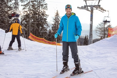 Man with ski equipment spending winter vacation at mountain resort