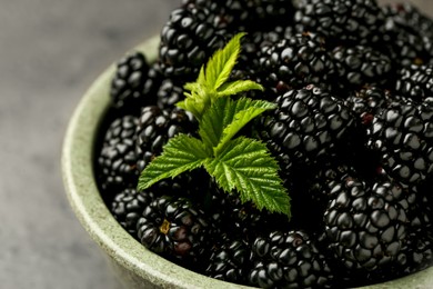Photo of Bowl with fresh ripe blackberries on grey table, closeup