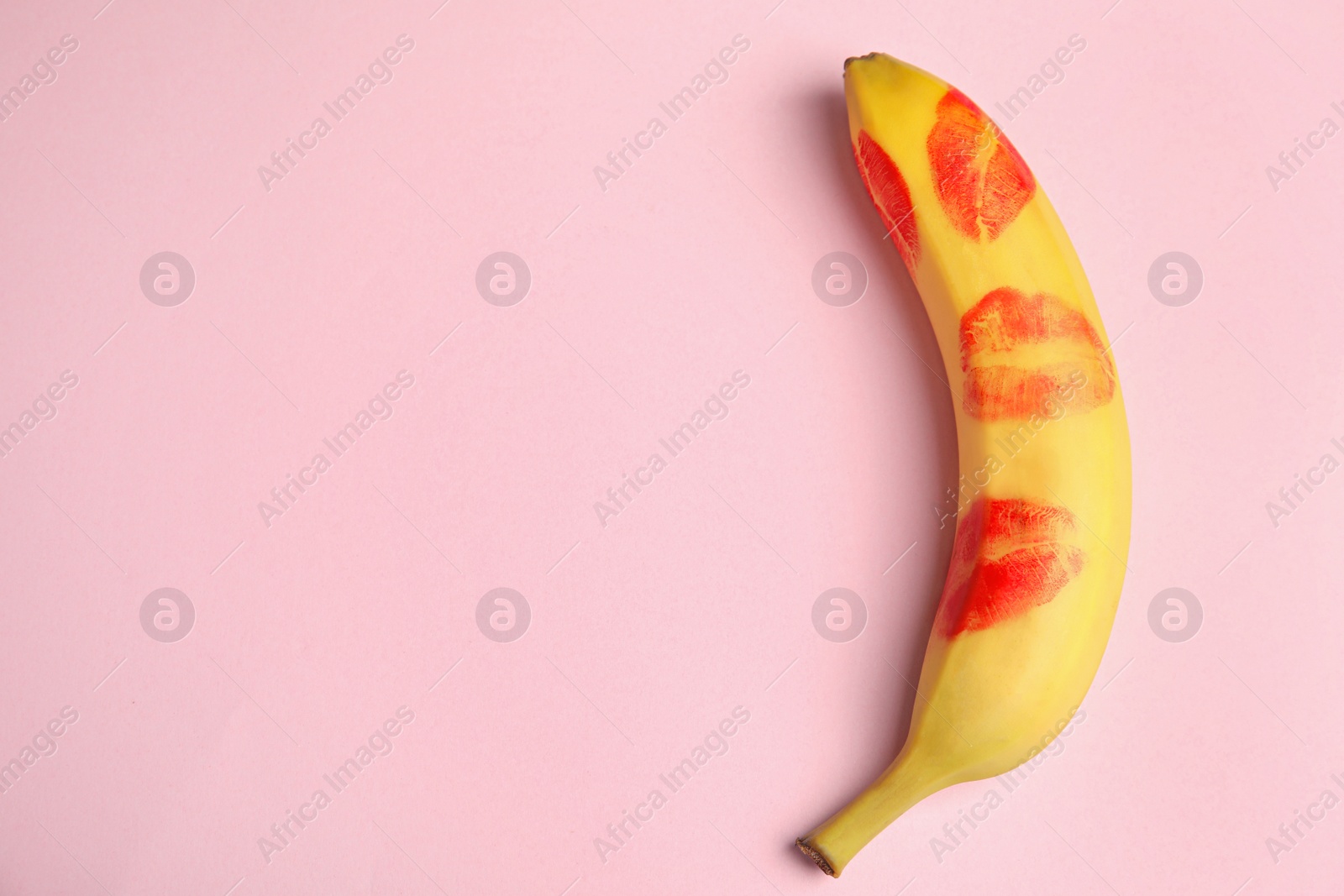 Photo of Top view of fresh banana with red lipstick marks on pink background, space for text. Oral sex concept