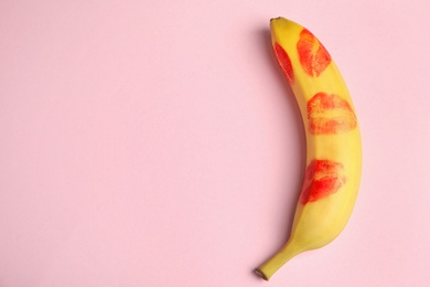 Top view of fresh banana with red lipstick marks on pink background, space for text. Oral sex concept