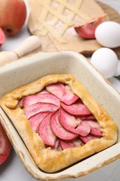 Delicious galette with apples and ingredients on light table, closeup