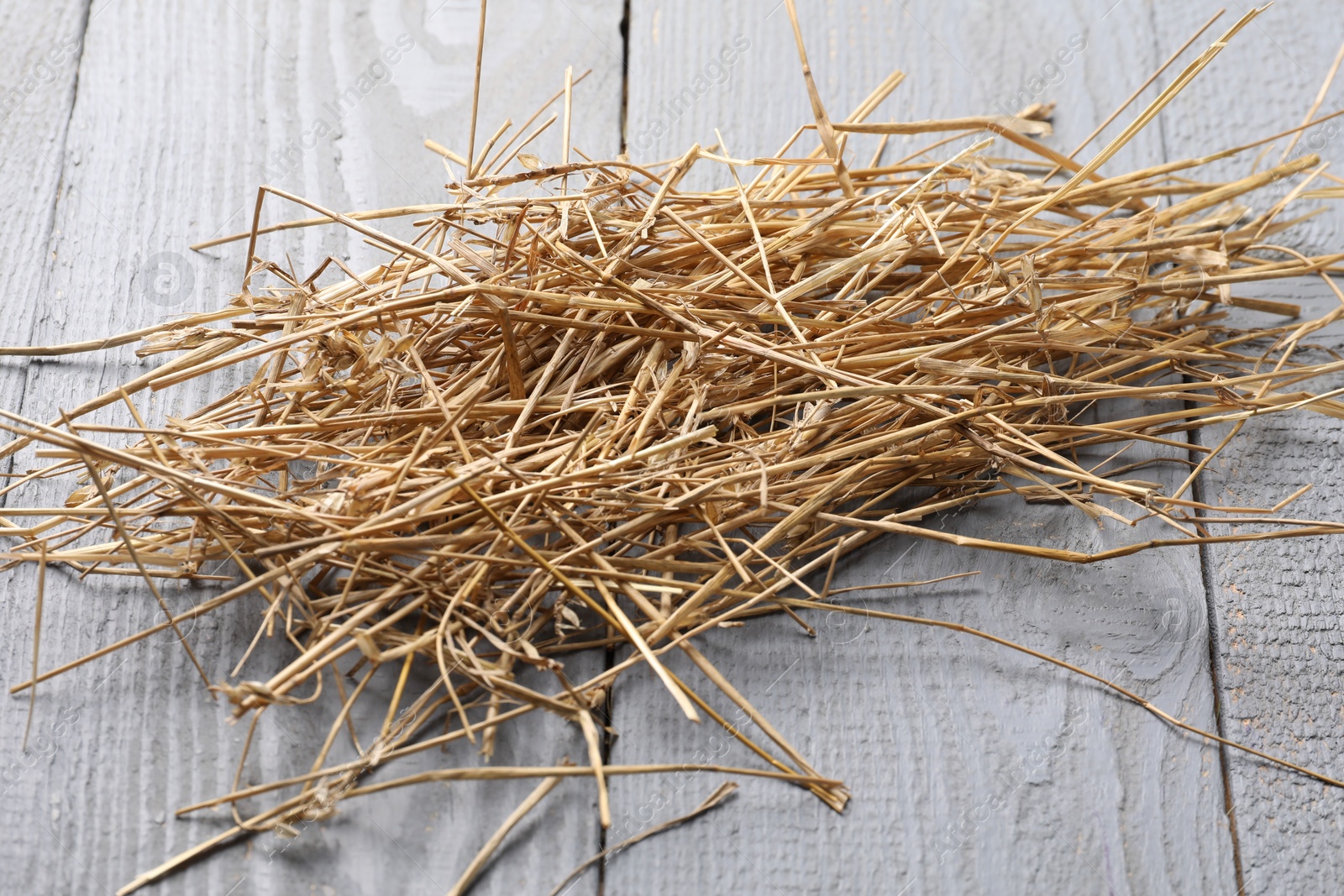 Photo of Pile of dried straw on grey wooden table