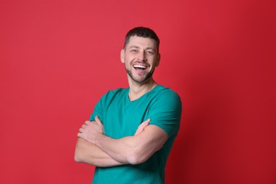 Photo of Handsome man laughing on red background. Funny joke