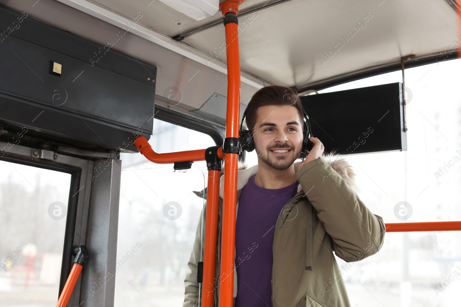 Photo of Young man listening to music with headphones in public transport