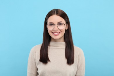 Portrait of woman in stylish eyeglasses on light blue background