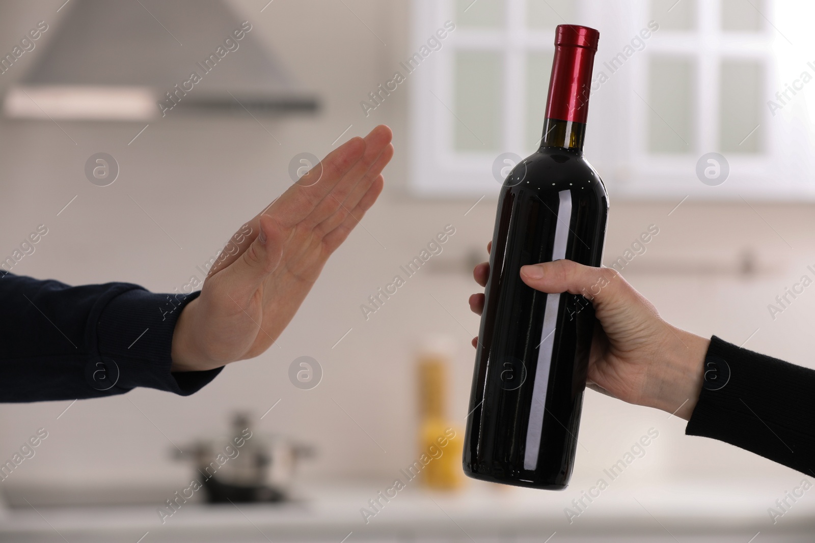 Photo of Man refusing to drink red wine in kitchen, closeup. Alcohol addiction treatment