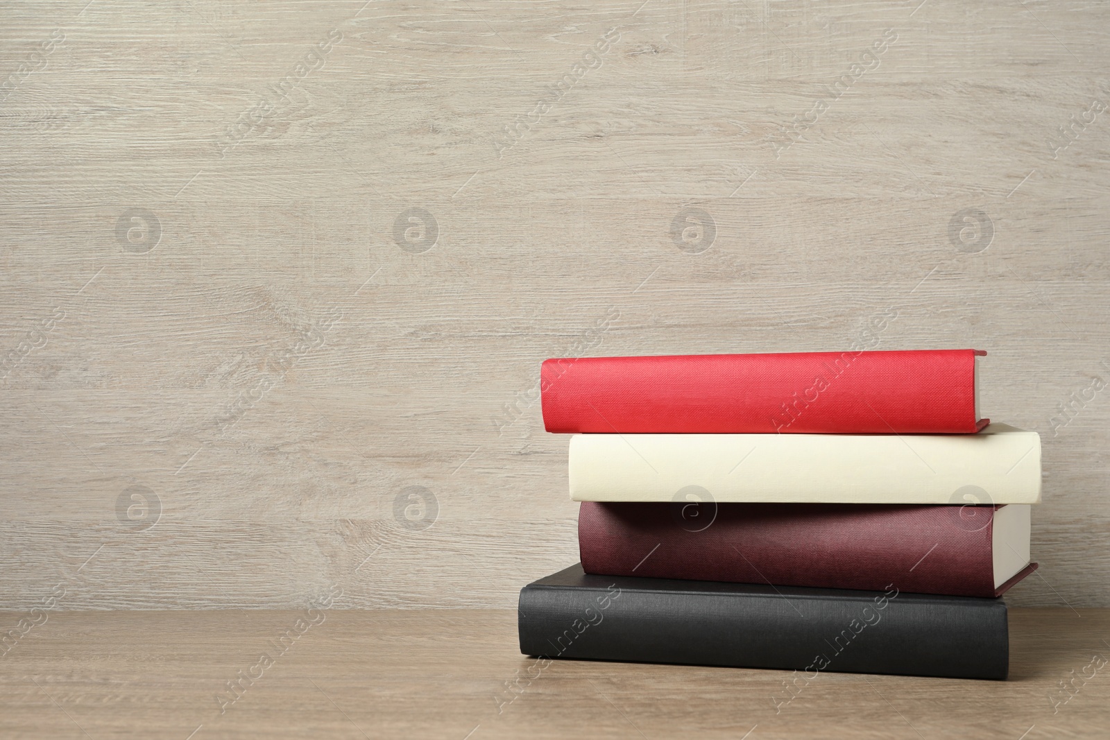 Photo of Stack of hardcover books on wooden table, space for text