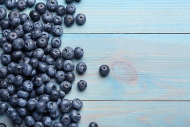 Photo of Tasty fresh blueberries on light blue wooden table, flat lay. Space for text