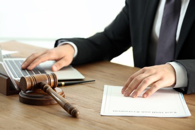 Male notary working with documents and laptop at table, closeup