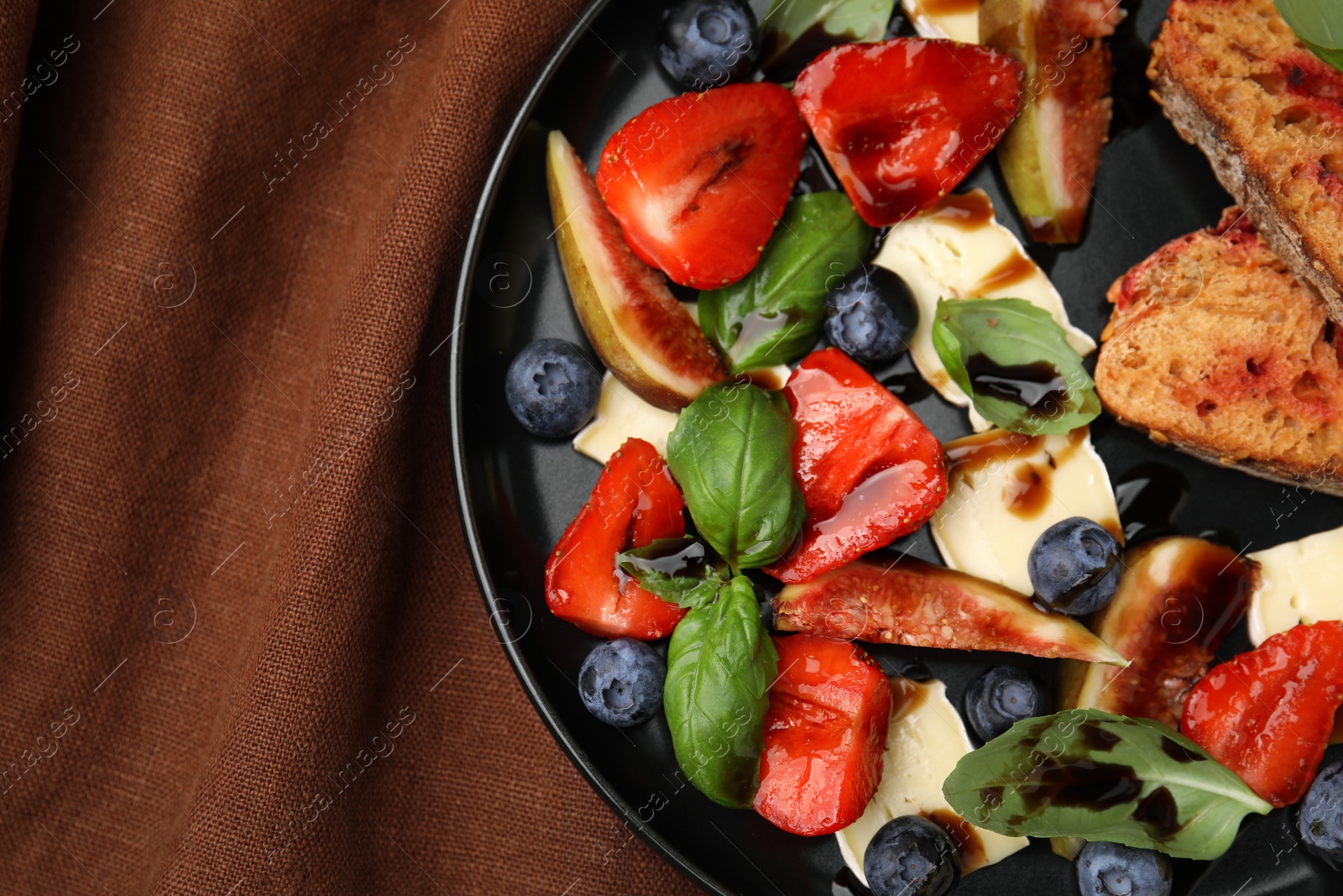 Photo of Delicious salad with brie cheese, blueberries, strawberries and balsamic vinegar on table, top view. Space for text