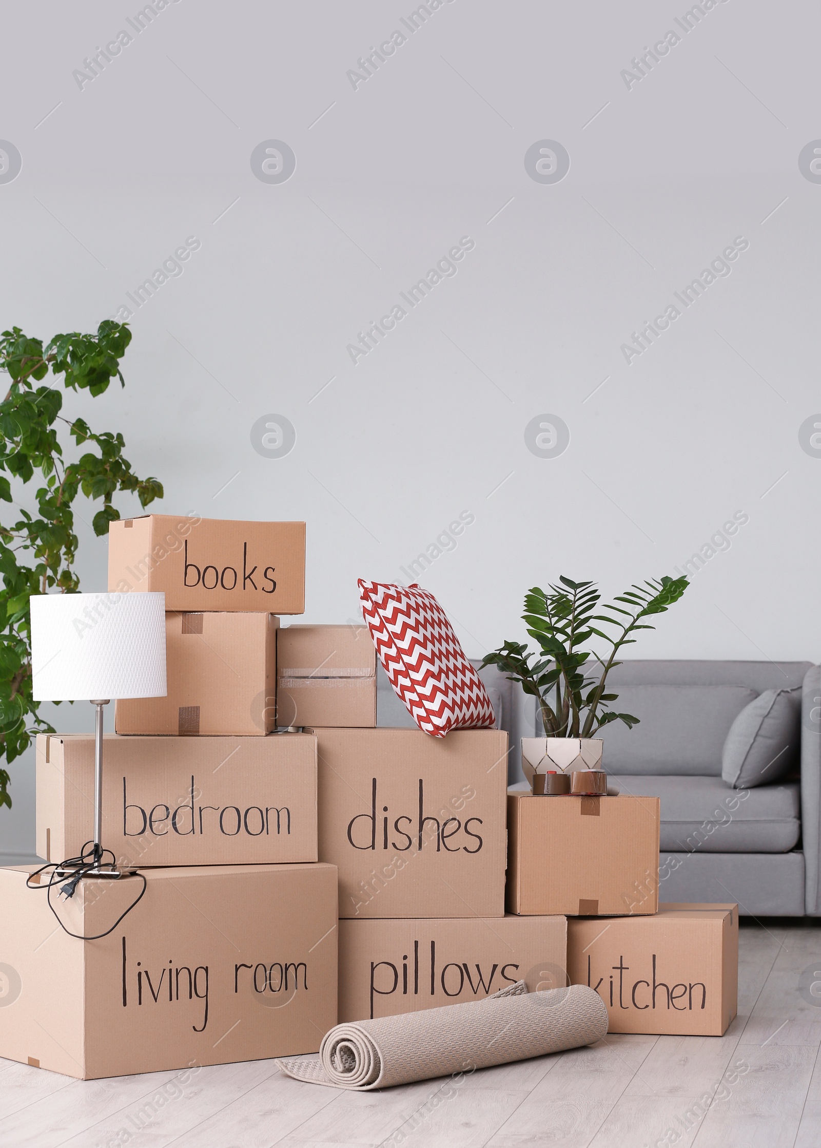 Photo of Pile of moving boxes and household stuff in living room