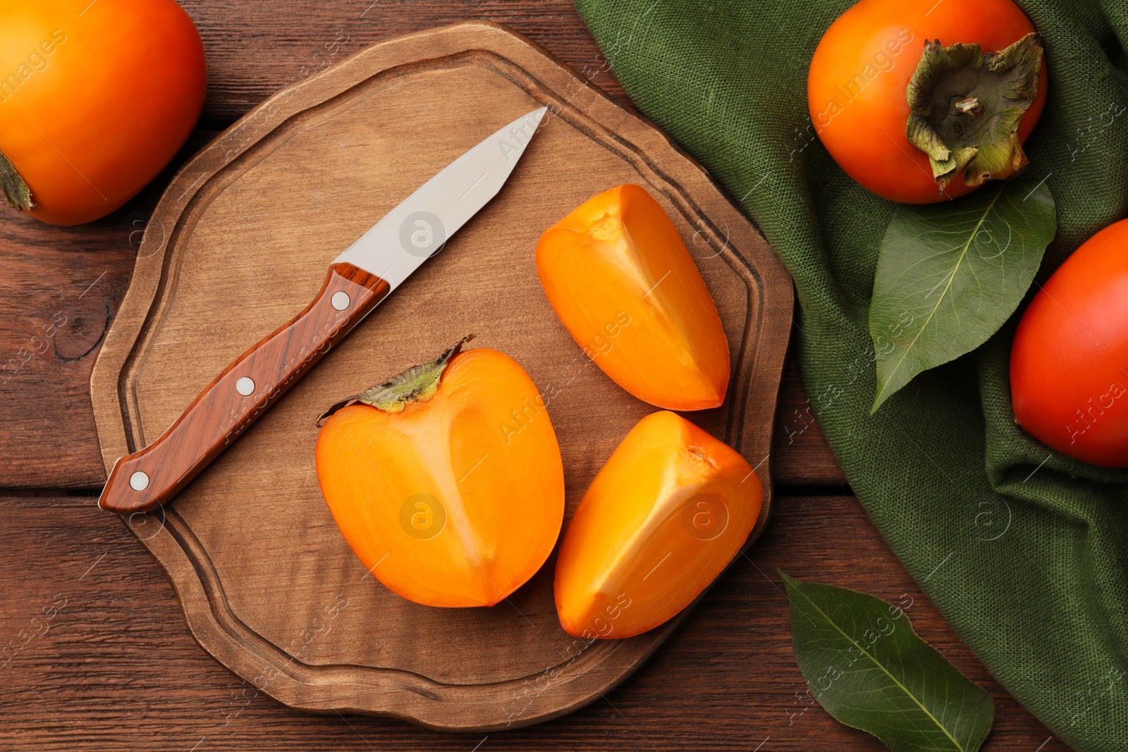 Photo of Delicious ripe persimmons and knife on wooden table, flat lay