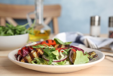 Photo of Delicious salad with roasted eggplant and arugula served on wooden table