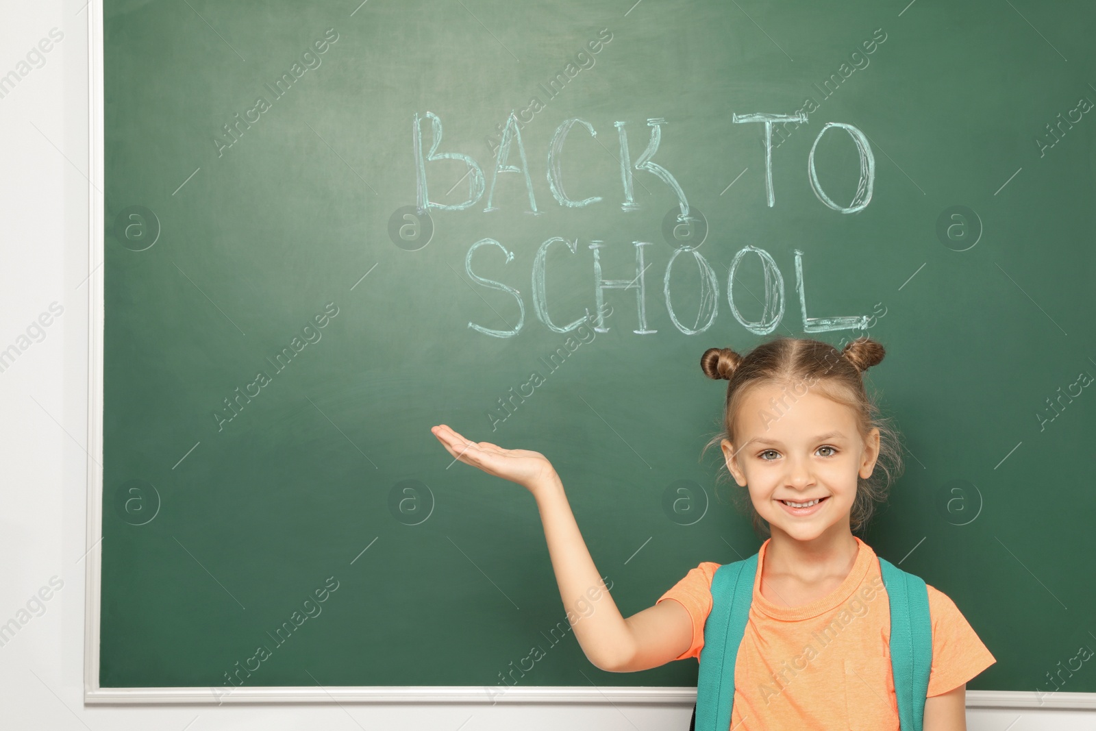 Photo of Little child near chalkboard with text BACK TO SCHOOL