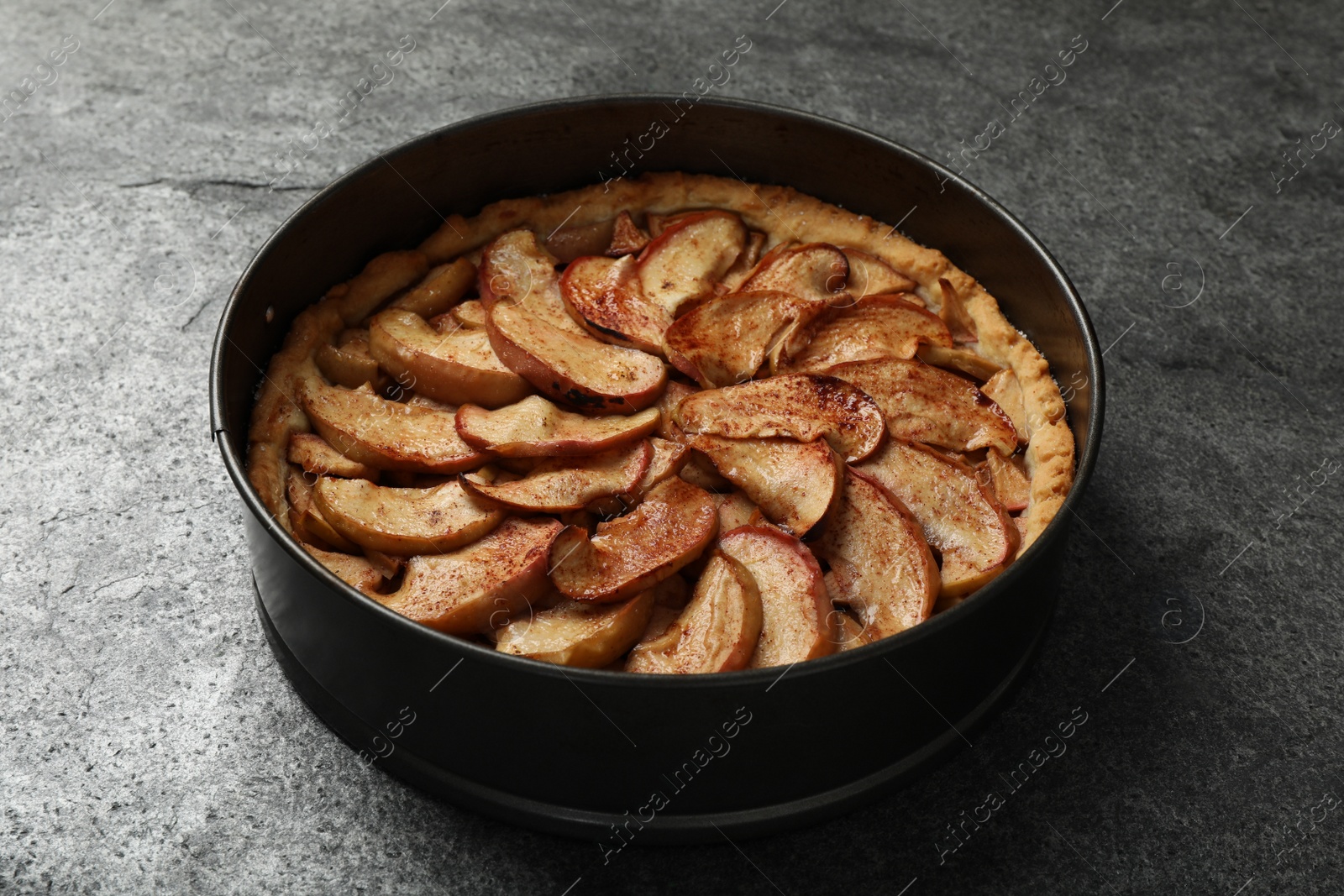 Photo of Delicious apple pie in baking dish on grey table