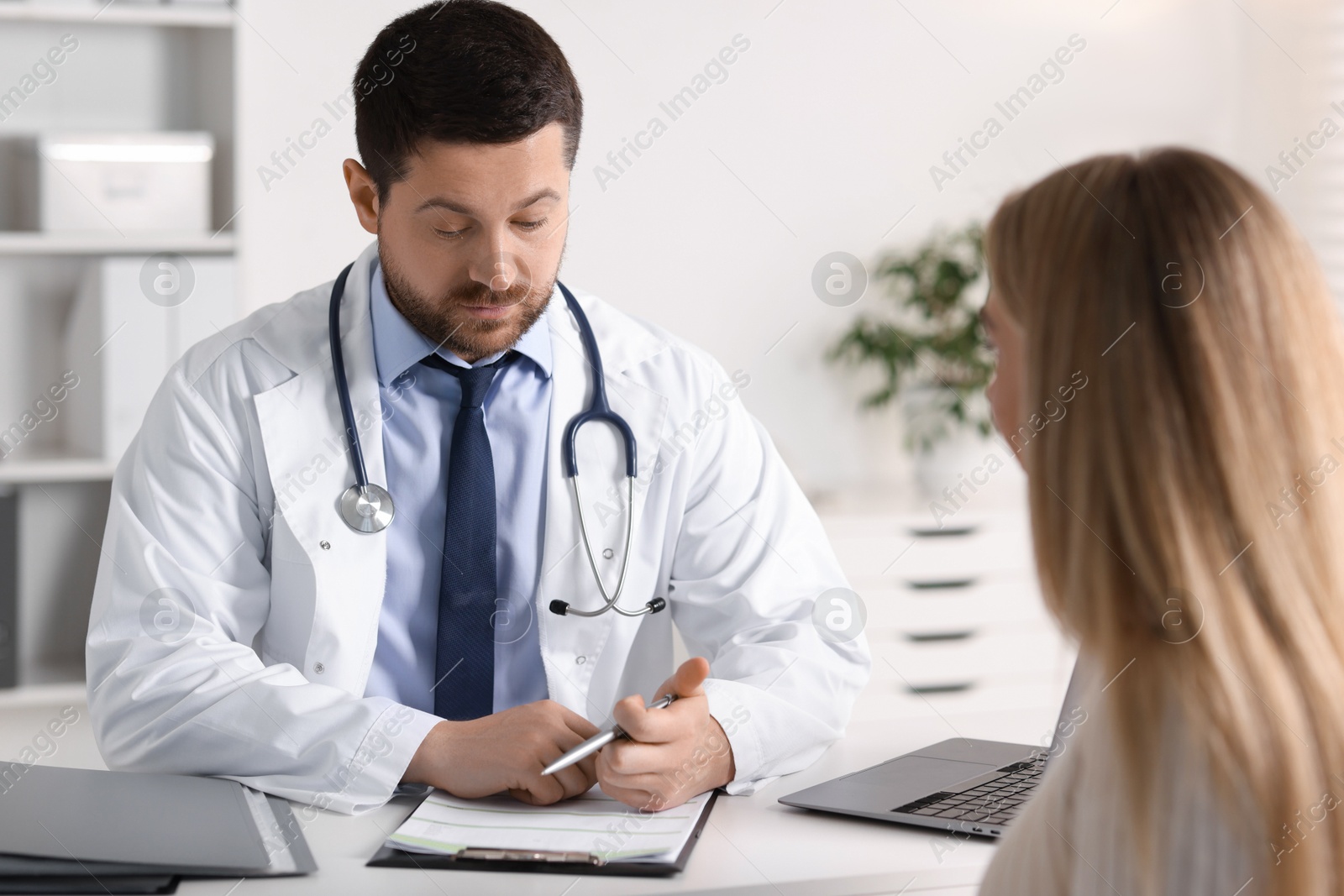 Photo of Professional doctor working with patient at white table in hospital