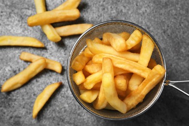 Frying basket with tasty french fries on grey table, flat lay