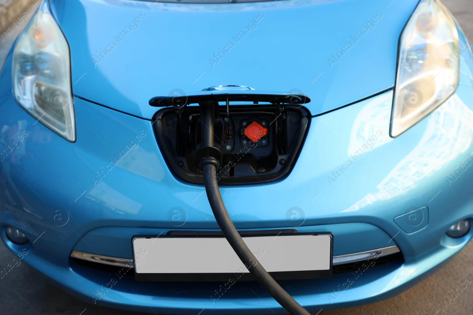 Photo of Charging modern electric car from station outdoors, closeup