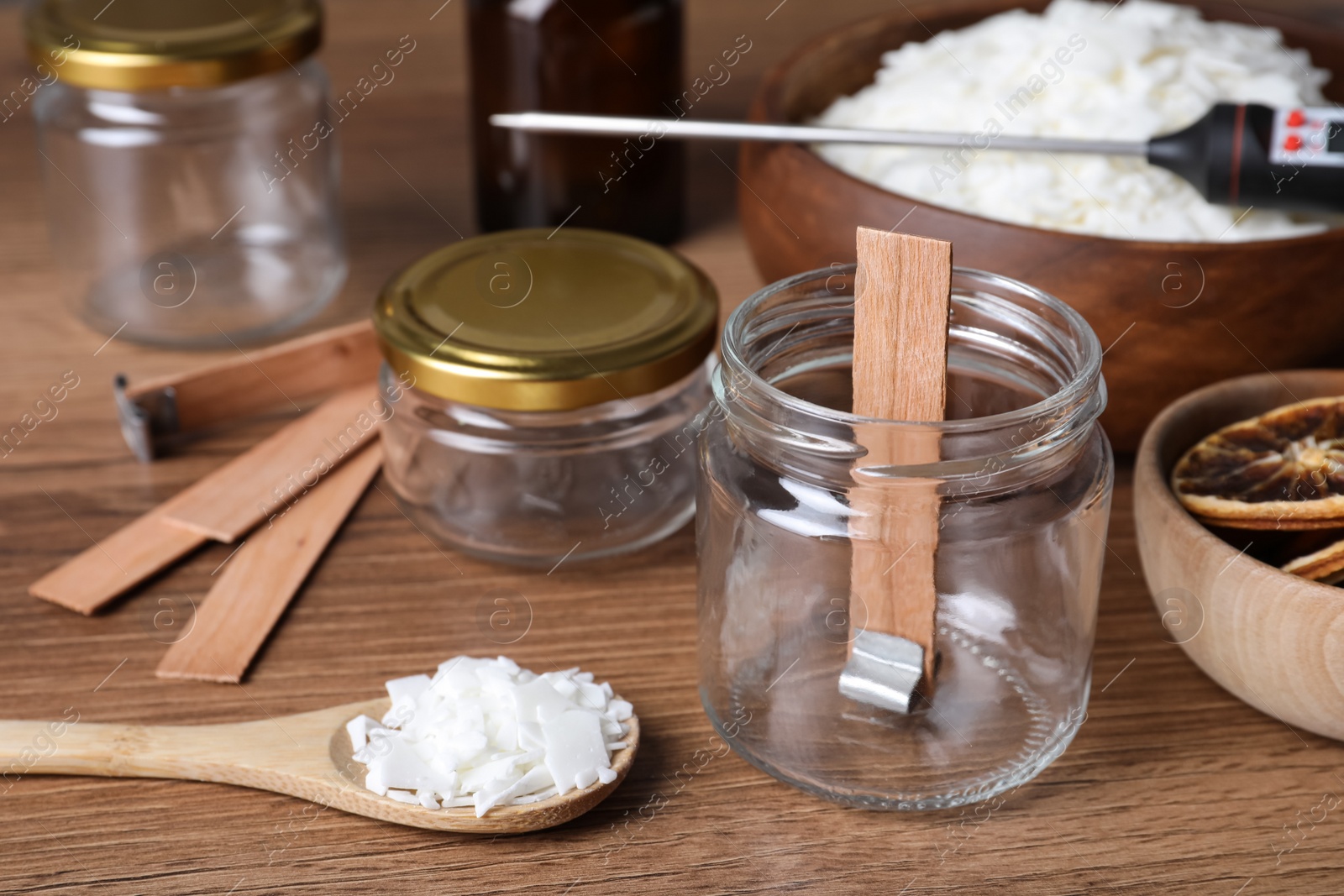 Photo of Glass jar with wick and wax flakes on wooden table. Making homemade candle