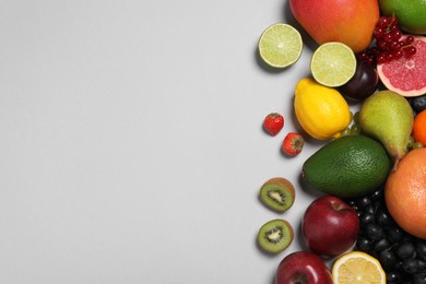 Photo of Many different fresh fruits and berries on light grey table, flat lay. Space for text