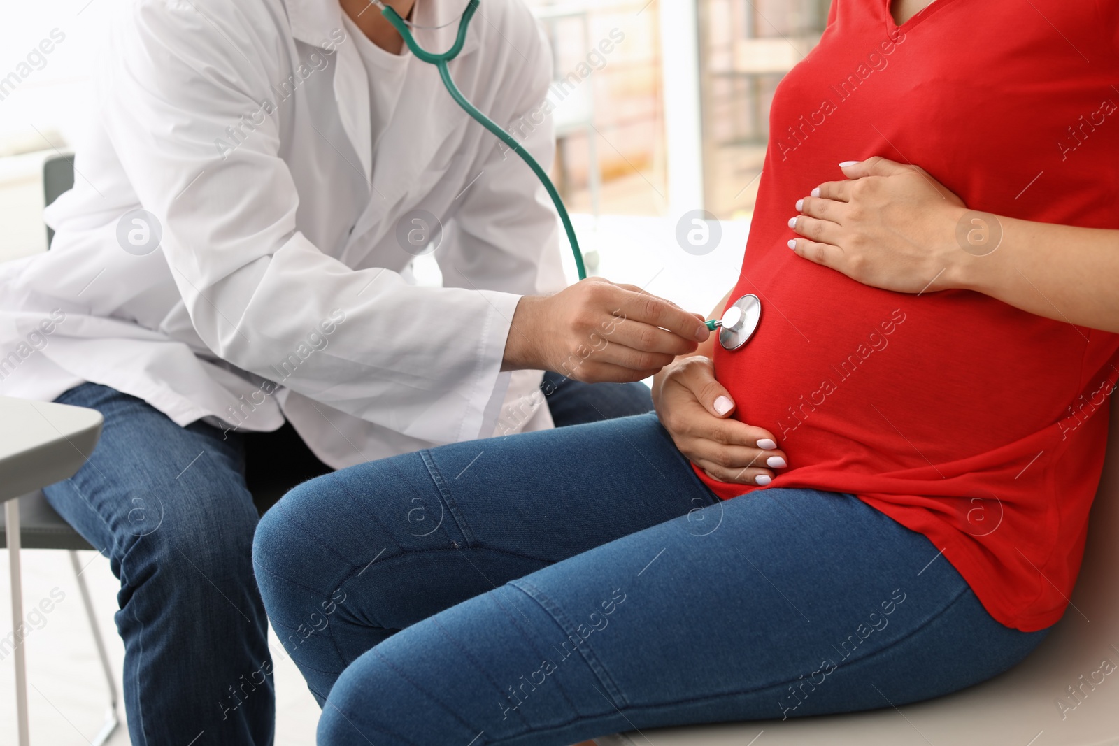 Photo of Young doctor examining pregnant woman in hospital. Patient consultation