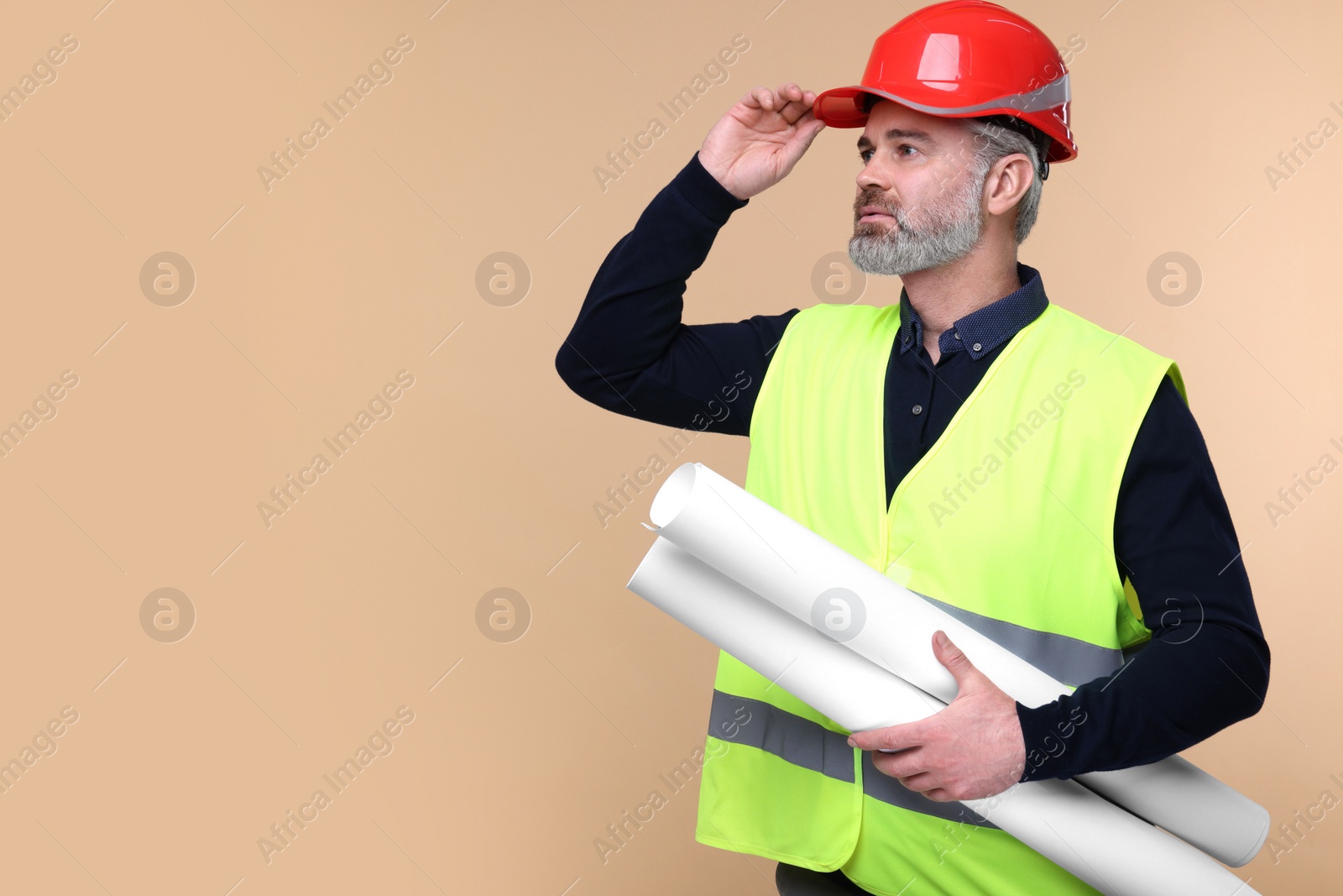 Photo of Architect in hard hat holding drafts on beige background. Space for text