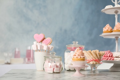 Photo of Candy bar with different sweets on white marble table against color background