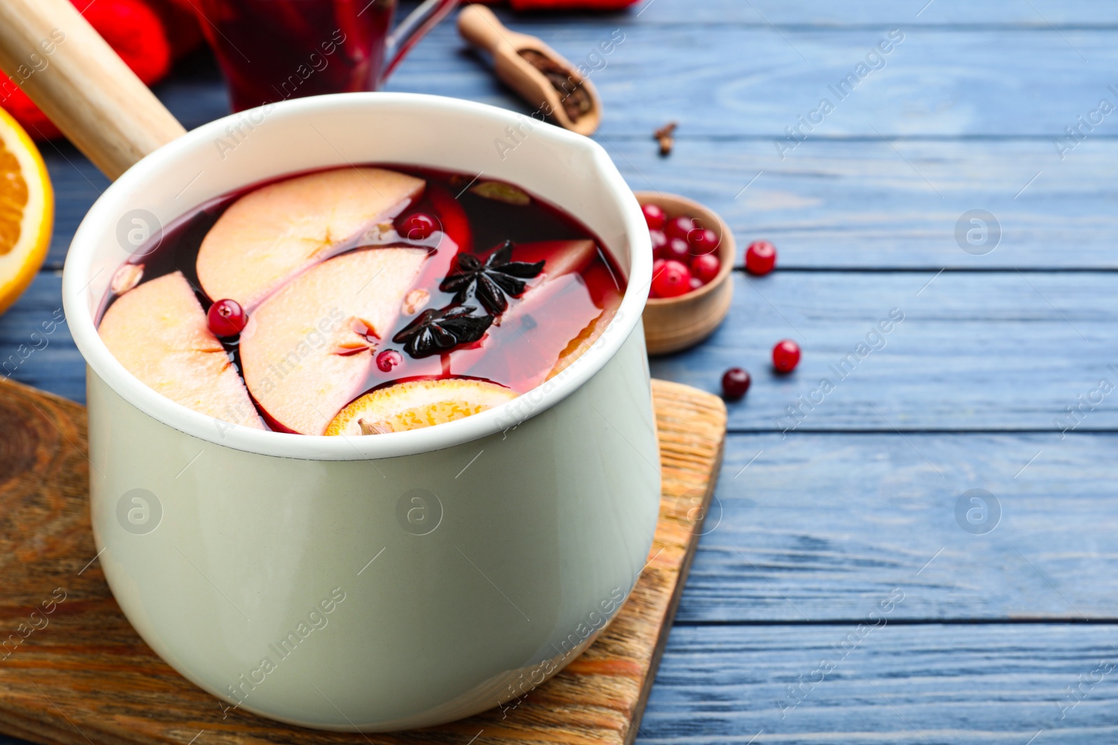 Photo of Delicious mulled wine and ingredients on blue wooden table, closeup. Space for text