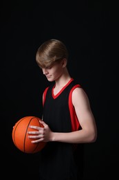 Photo of Teenage boy with basketball ball on black background