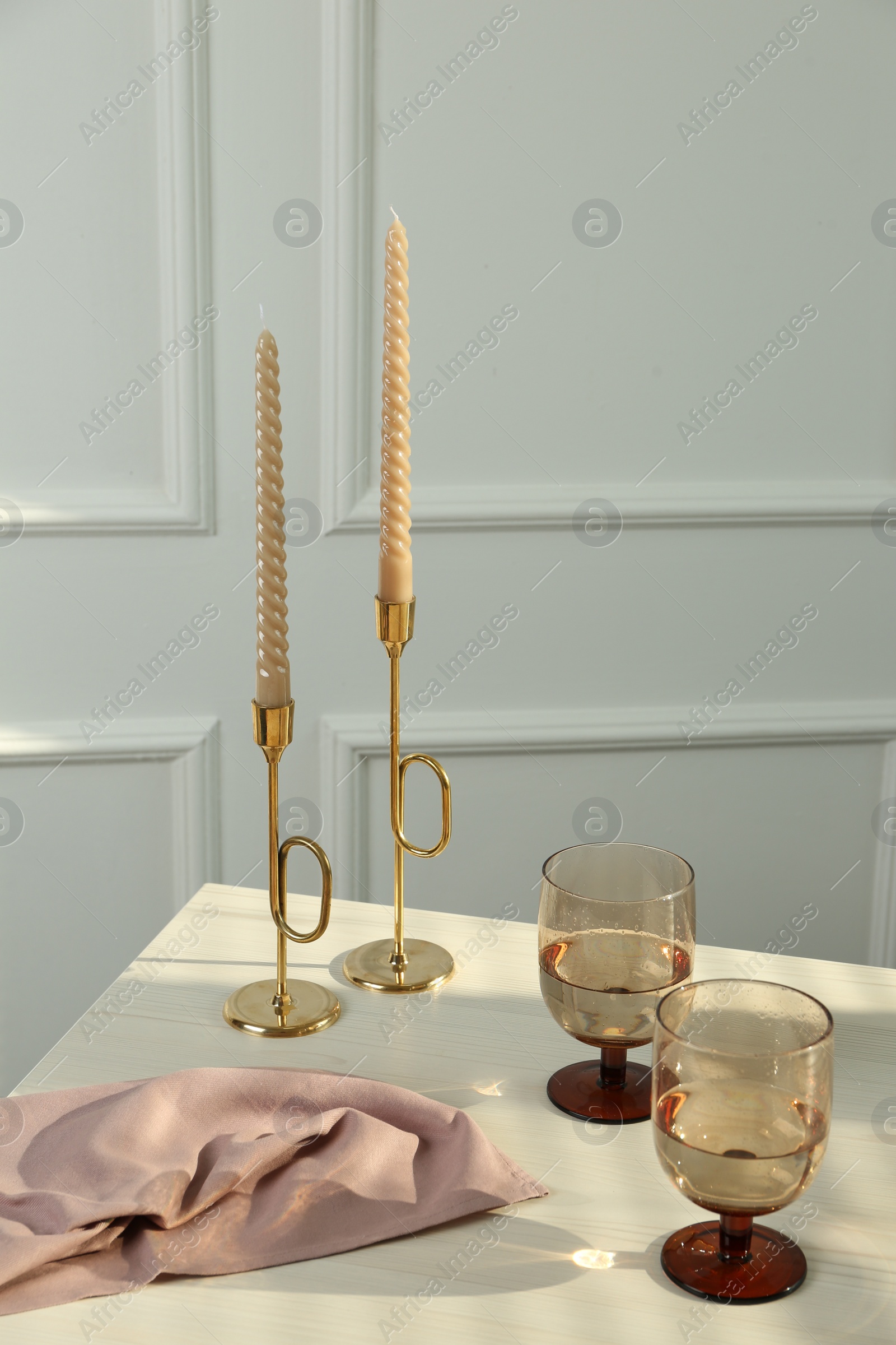Photo of Glasses of wine near candles on white table indoors