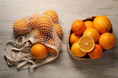 Many whole and cut oranges on wooden table, flat lay