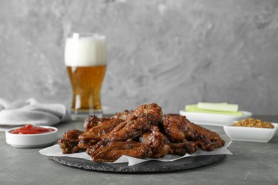 Delicious chicken wings served with beer on grey table