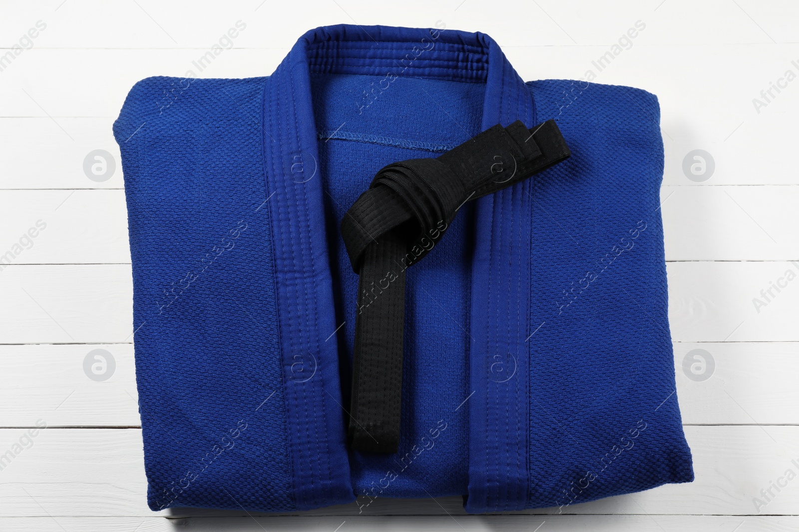 Photo of Black karate belt and blue kimono on wooden background, top view