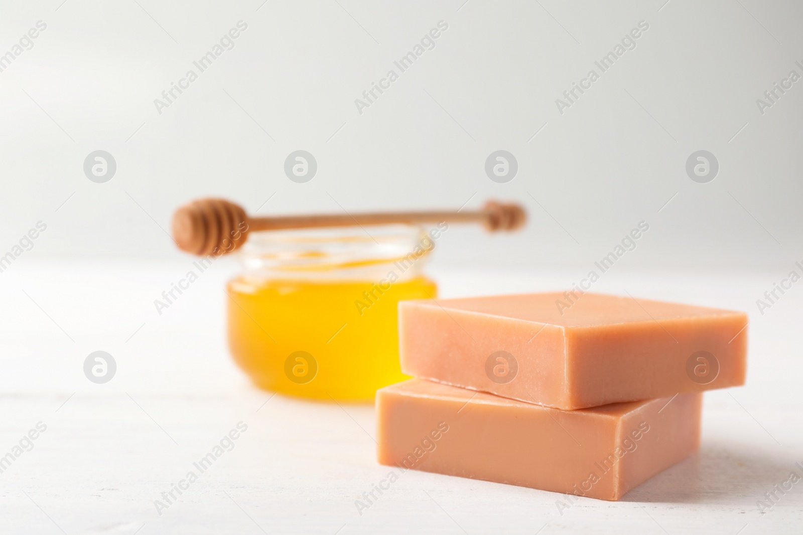 Photo of Handmade soap bars and jar of honey on white table. Space for text