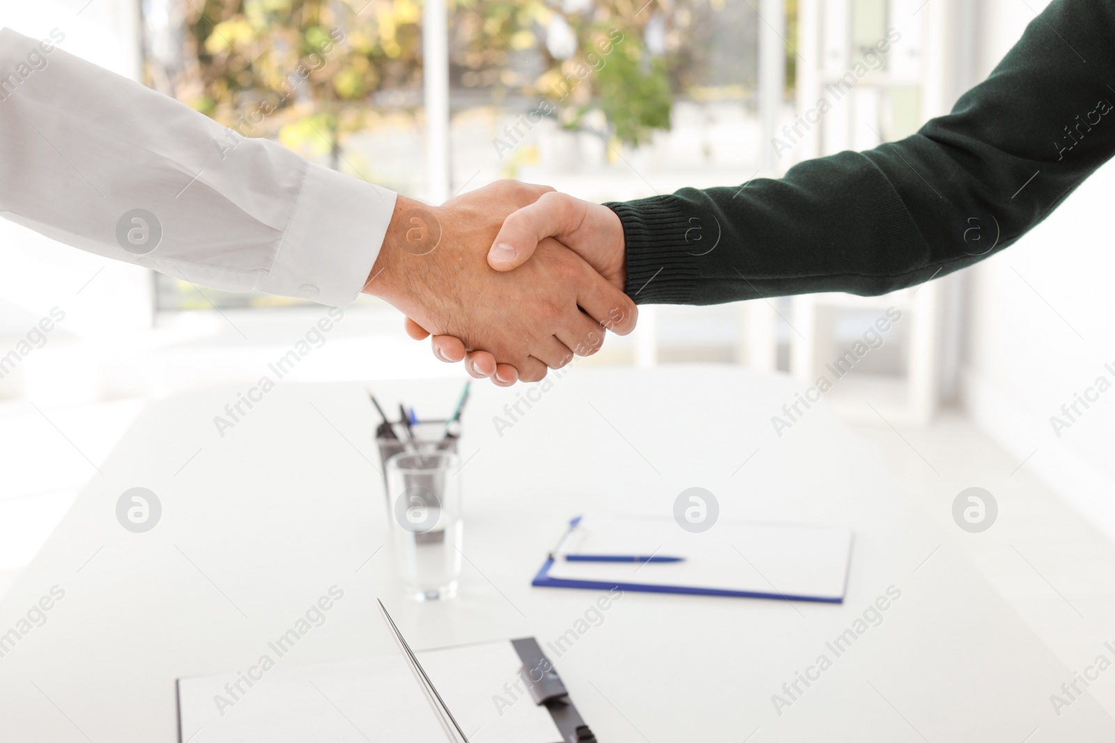 Photo of Human resources manager shaking hands with applicant during job interview in office, closeup