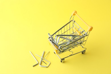 Photo of Small shopping cart with hexagon wrench set on yellow background. Construction tools