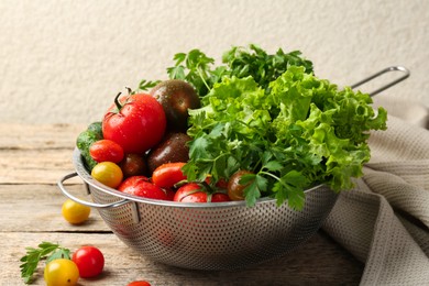 Photo of Wet vegetables in colander on wooden table, closeup